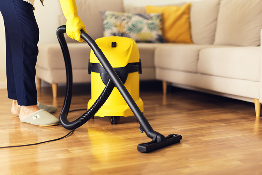 woman cleaning sofa with yellow vacuum cleaner